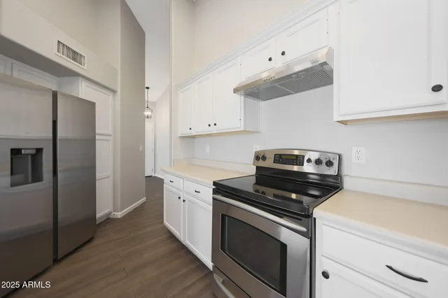 a kitchen with cabinets stainless steel appliances and wooden floor