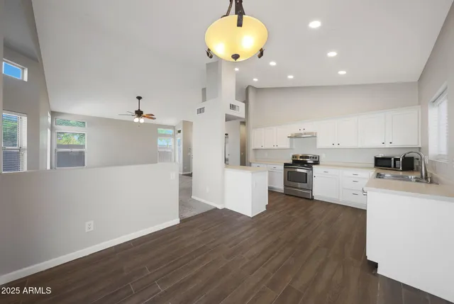 a kitchen with stainless steel appliances granite countertop a refrigerator a stove a sink dishwasher and white cabinets with wooden floor