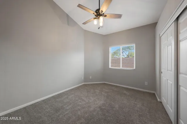 an empty room with a chandelier fan and windows