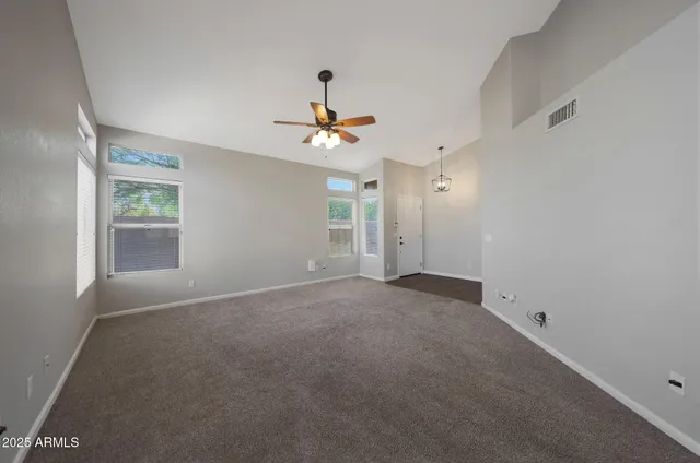 an empty room with windows and chandelier fan