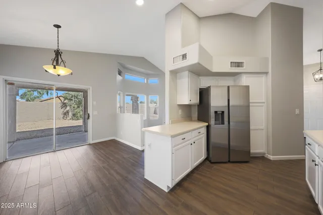 a kitchen with stainless steel appliances granite countertop a refrigerator a sink dishwasher a stove and white countertops with wooden floor