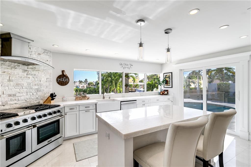 2948 Northeast 35th Court Lighthouse Point, FL 33064 - Photo 11 of 24 a kitchen with stainless steel appliances granite countertop a stove a refrigerator a sink and a dining table with white cabinets