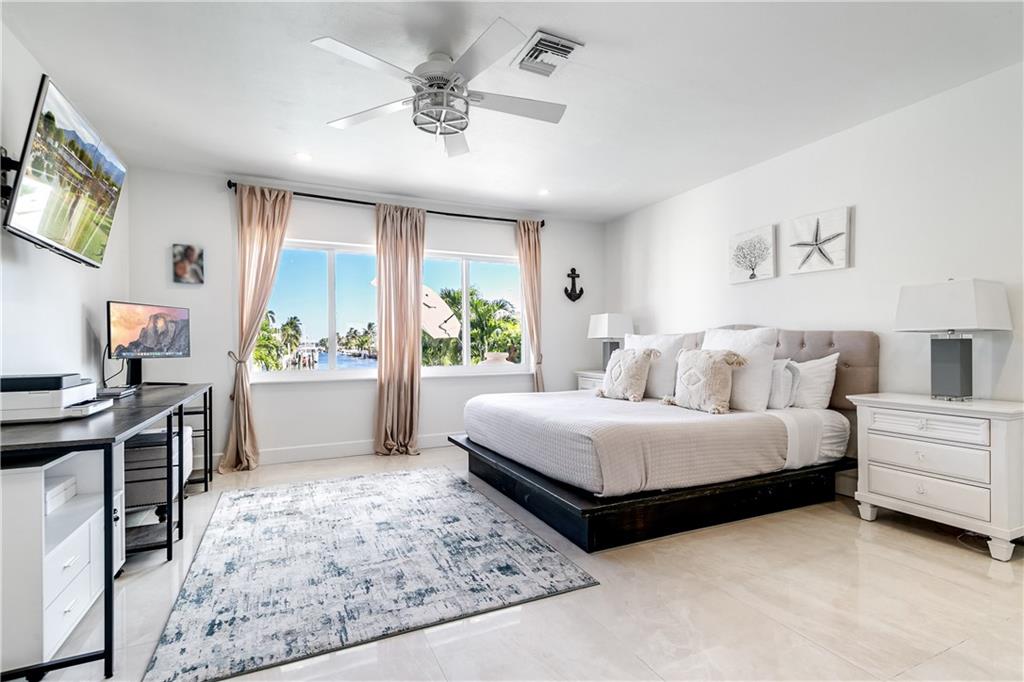 2948 Northeast 35th Court Lighthouse Point, FL 33064 - Photo 14 of 24 a spacious bedroom with a bed a couch and a window