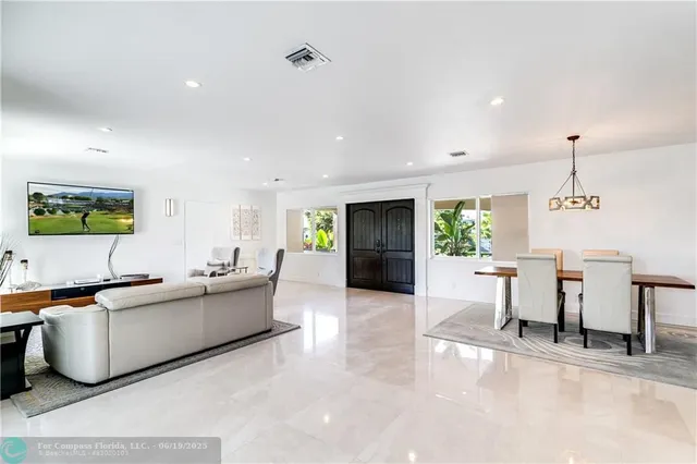 a large living room with stainless steel appliances kitchen island granite countertop furniture a rug and a large window