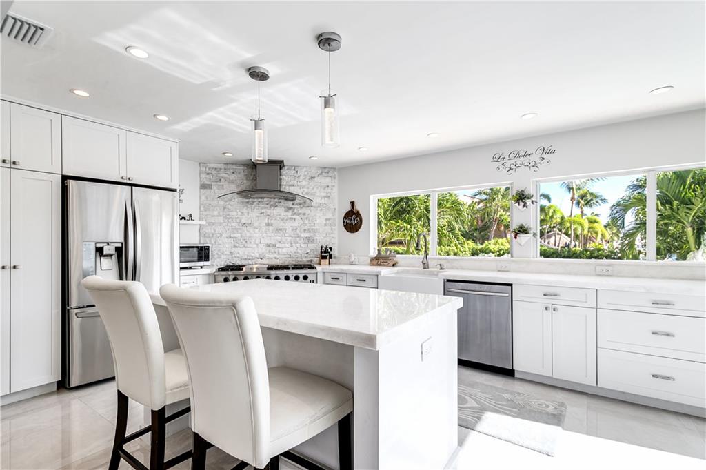 2948 Northeast 35th Court Lighthouse Point, FL 33064 - Photo 9 of 24 a large kitchen with kitchen island a large window a sink stainless steel appliances and cabinets