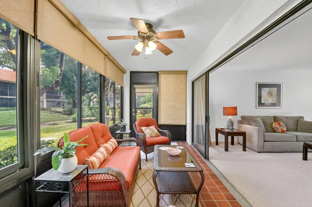 a living room with furniture a ceiling fan and a large window