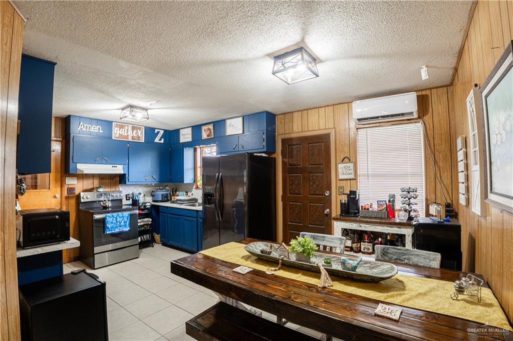 425 South Reynolds Rio Hondo, TX 78583 - Photo 11 of 23 The property features a kitchen and dining area with wood paneling, blue cabinetry, and stainless steel appliances