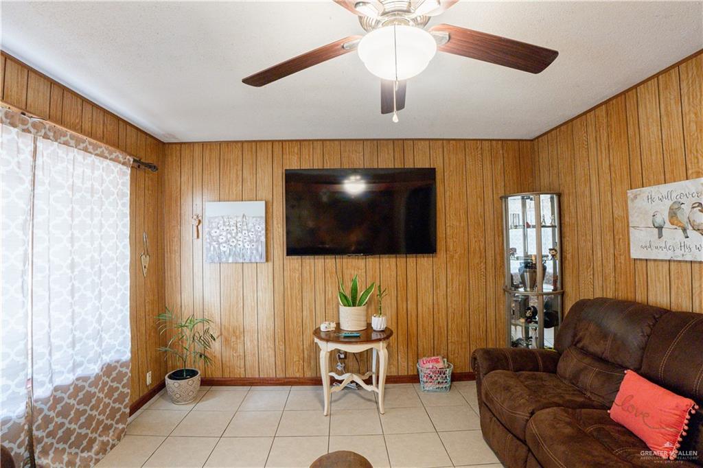 425 South Reynolds Rio Hondo, TX 78583 - Photo 4 of 23 Living area featuring wood paneling on the walls, a ceiling fan with integrated lighting, and tile flooring