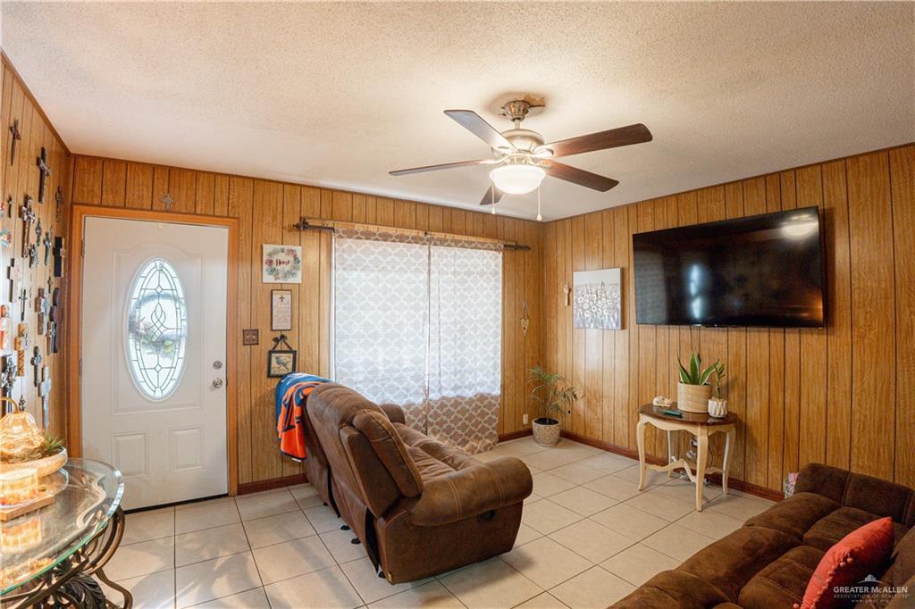 425 South Reynolds Rio Hondo, TX 78583 - Photo 6 of 23 Living area featuring wood paneling on the walls, tiled flooring, and a ceiling fan with integrated lighting