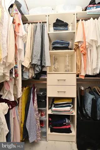 a view of walk in closet with clothes and shoes