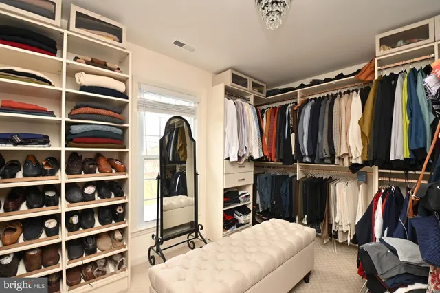 a view of walk in closet with clothes and shoes