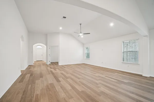 a view of empty room with wooden floor and fan