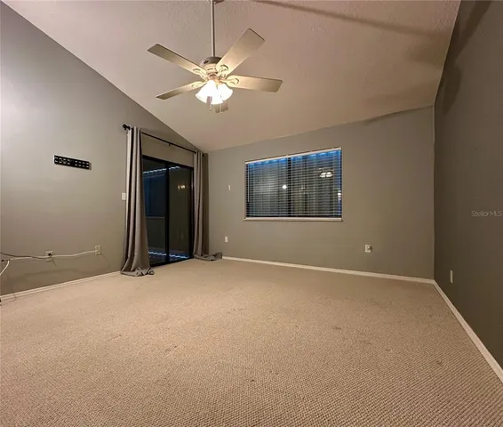 an empty room with chandelier fan and windows