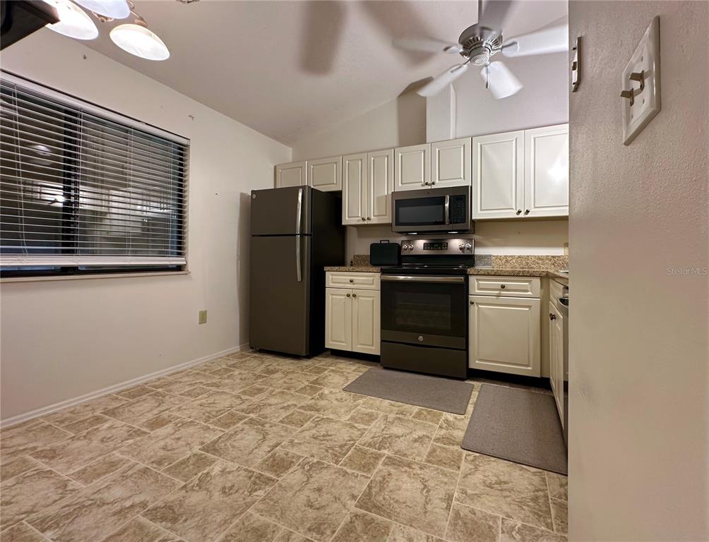 5685 Marina Drive, Unit 4 Sebastian, FL 32958 - Photo 10 of 19 a kitchen with stainless steel appliances granite countertop a stove a refrigerator a sink a microwave oven with white cabinets