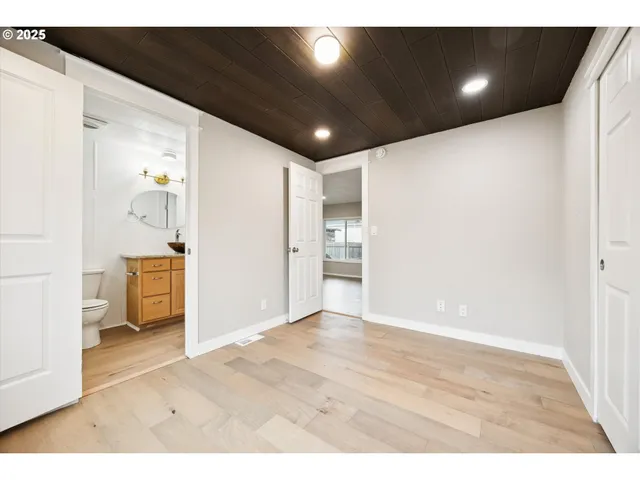 a view of an empty room with wooden floor and windows
