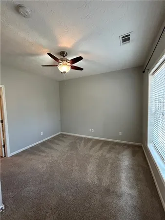 an empty room with a window and a ceiling fan