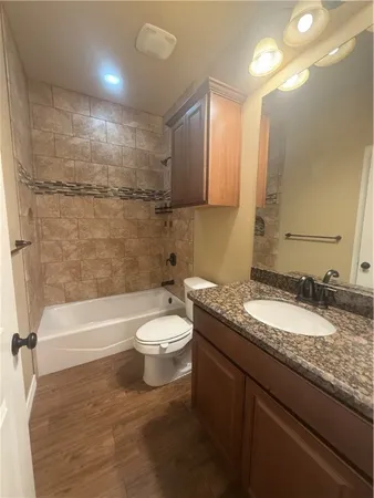 a bathroom with a granite countertop sink a toilet a mirror and bathtub