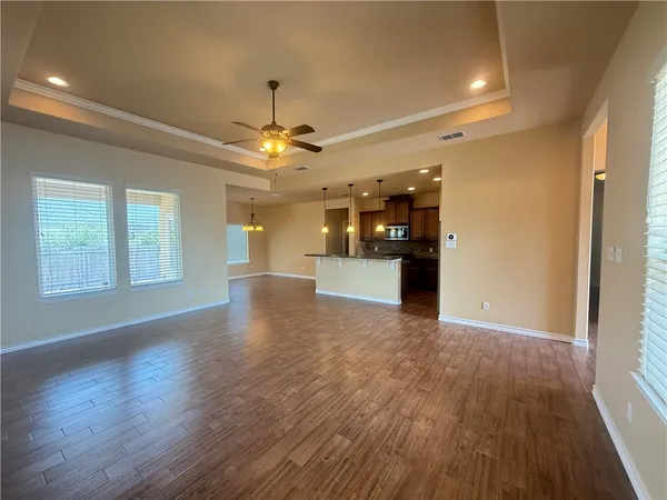 a view of a big room with wooden floor a kitchen view and windows