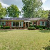 a front view of a house with a yard and trees