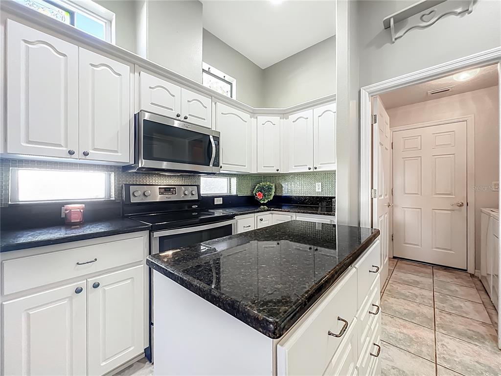 5685 Gulf Stream Street Tavares, FL 32778 - Photo 49 of 78 a kitchen with stainless steel appliances granite countertop a sink a stove a microwave and cabinets