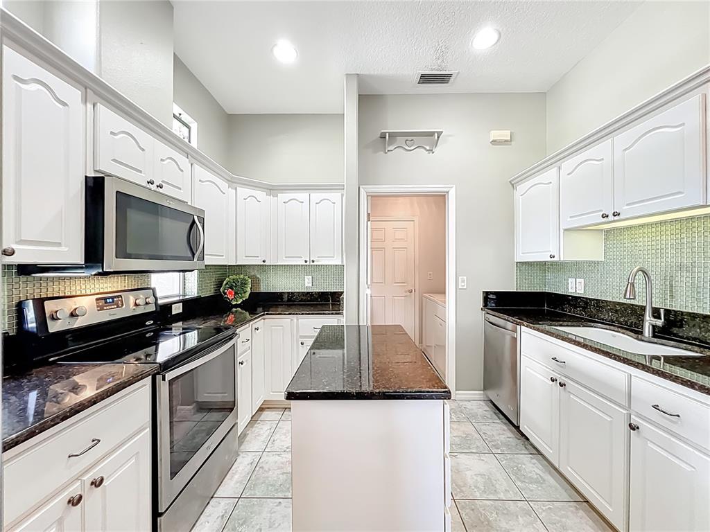 5685 Gulf Stream Street Tavares, FL 32778 - Photo 50 of 78 a kitchen with granite countertop a sink stainless steel appliances and white cabinets