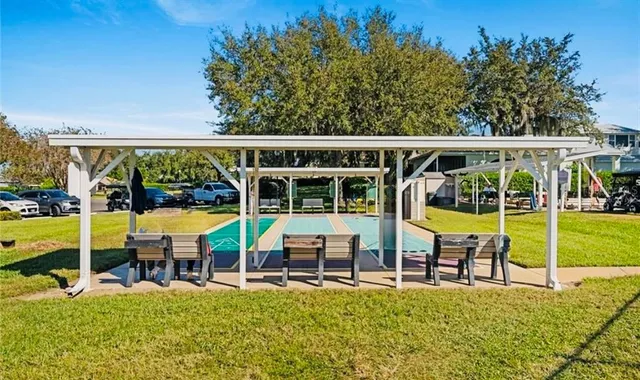 a view of a swimming pool with lawn chairs and large trees
