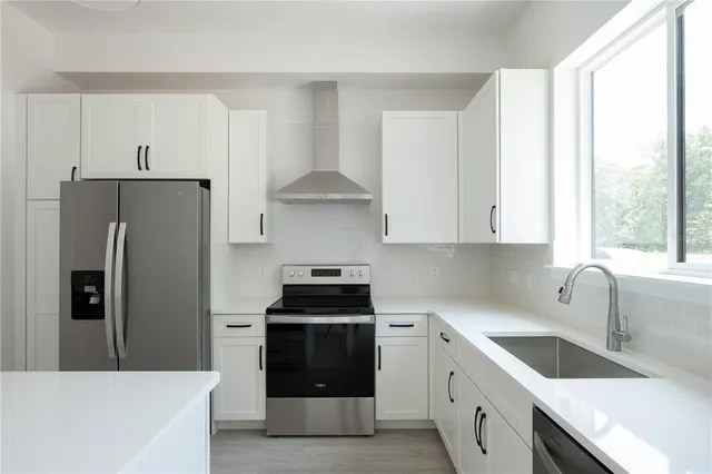 a kitchen with stainless steel appliances white cabinets and a refrigerator