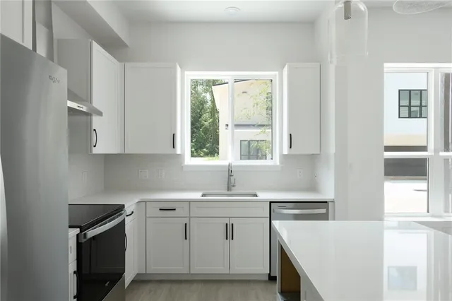 a kitchen with cabinets appliances a sink and a window