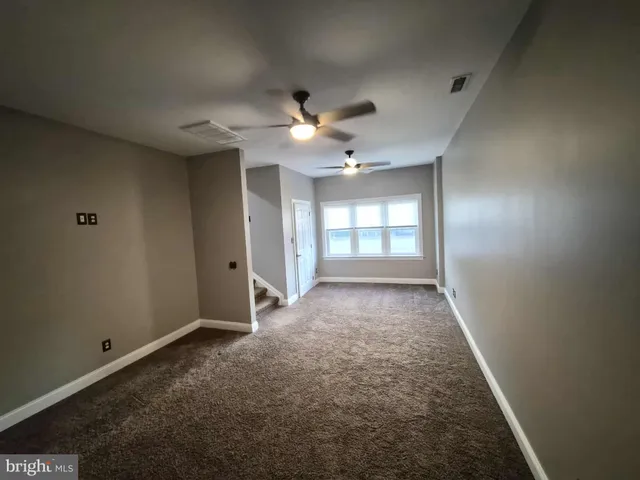 an empty room with chandelier fan and windows
