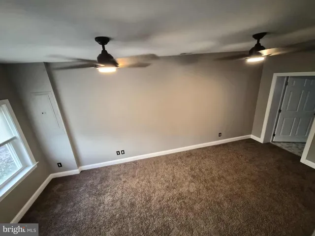 an empty room with ceiling fan and window