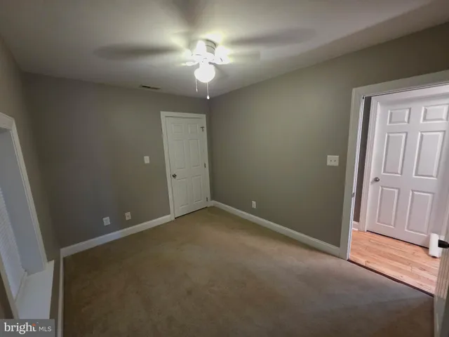 an empty room with chandelier fan and windows