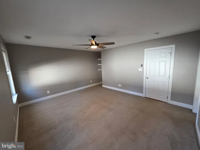 an empty room with a ceiling fan and a window