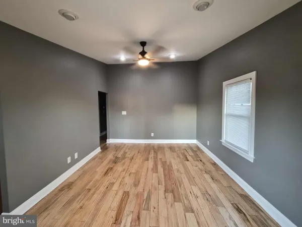 an empty room with wooden floor chandelier fan and windows
