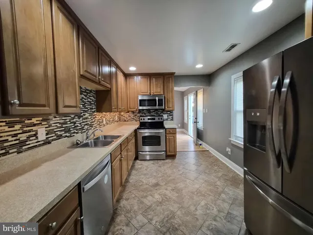 a kitchen with stainless steel appliances granite countertop a refrigerator a stove a sink and a microwave