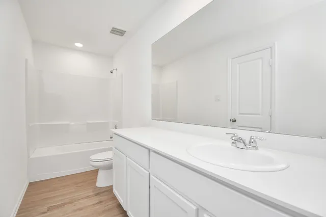 a bathroom with a granite countertop sink a toilet and shower
