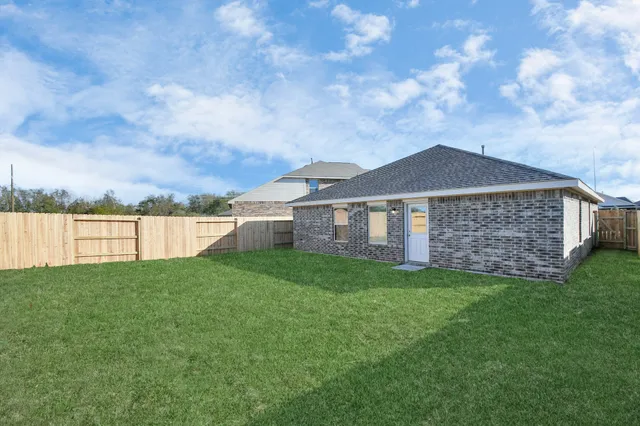 a view of a yard in front of a house with plants and large trees