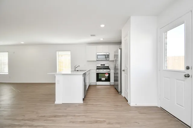 a kitchen with wooden floors and white cabinets