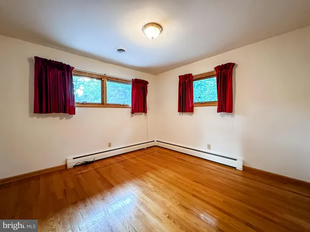 a view of an empty room with window and wooden floor