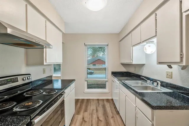 a kitchen with granite countertop a sink stove and cabinets