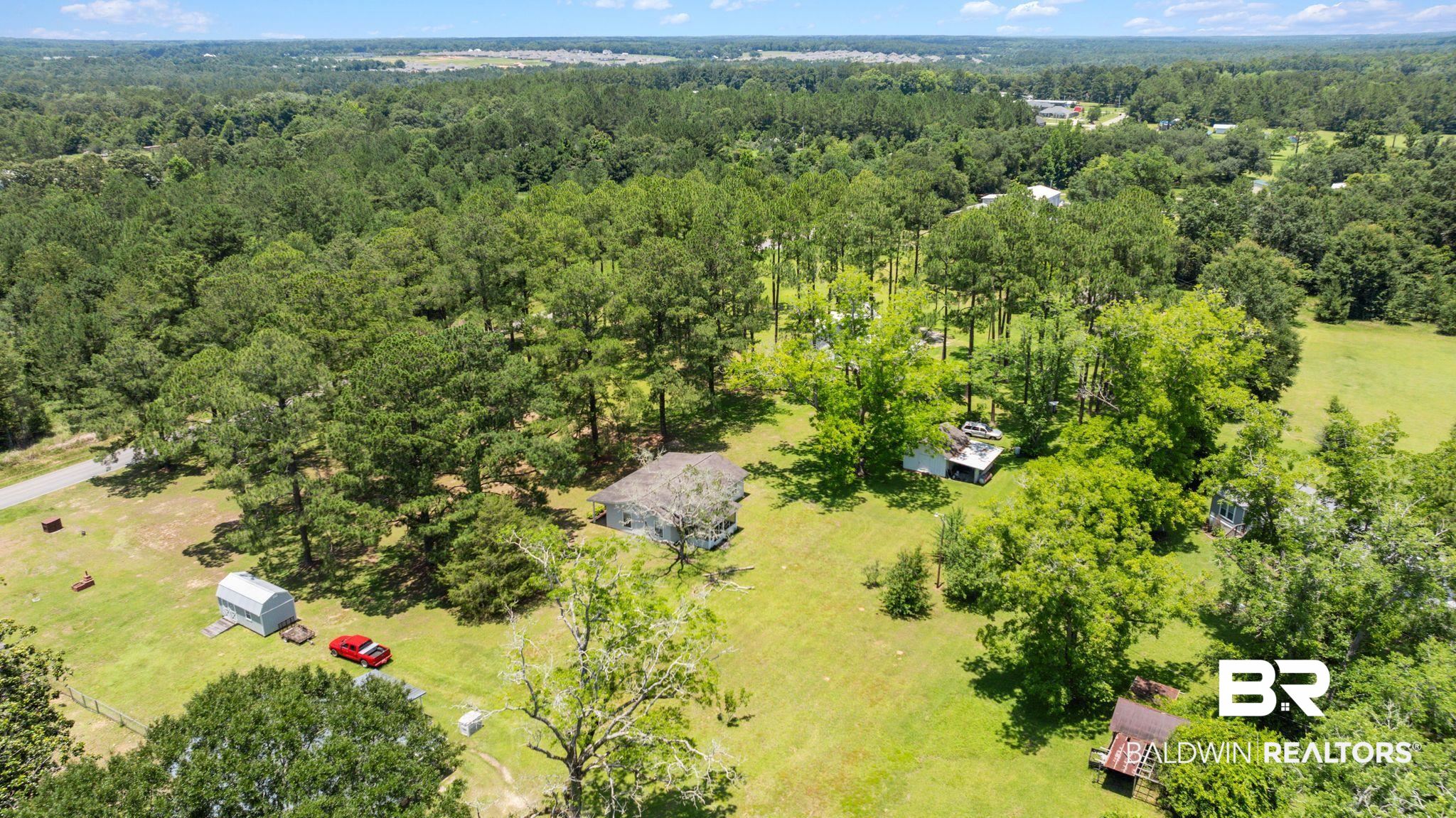 20540 Lacey Road Silverhill, AL 36576 - Photo 34 of 40 Expansive property featuring a mix of mature deciduous and evergreen trees, a gravel driveway, and a detached outbuilding