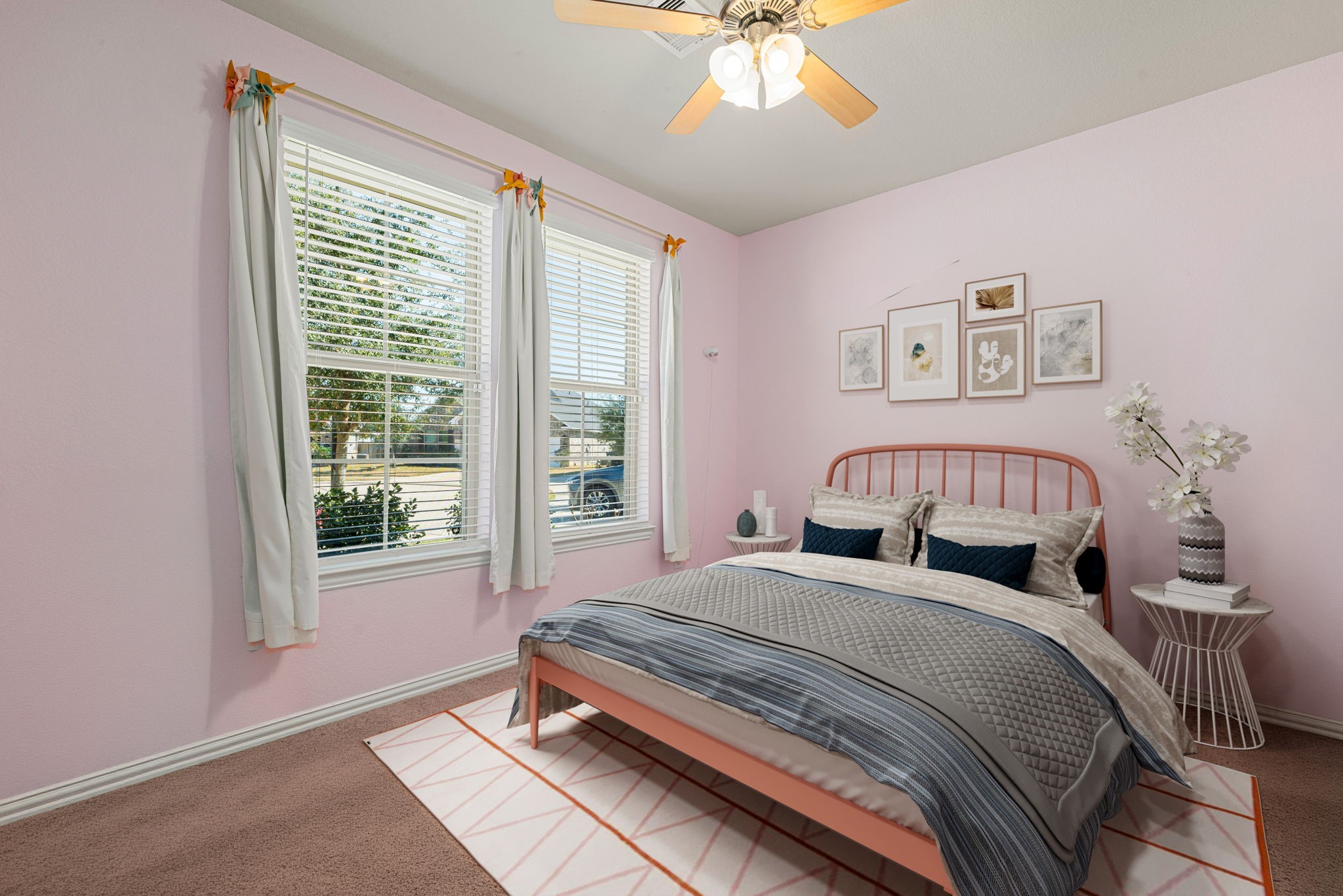 8414 Divot Trace Fulshear, TX 77441 - Photo 16 of 25 This bright bedroom features large double windows that flood the space with natural light. The room is finished with neutral-toned flooring, soft pastel walls, and a modern ceiling fan with integrated lighting. Its clean lines and airy atmosphere create a versatile and inviting retreat for guests or a home office.