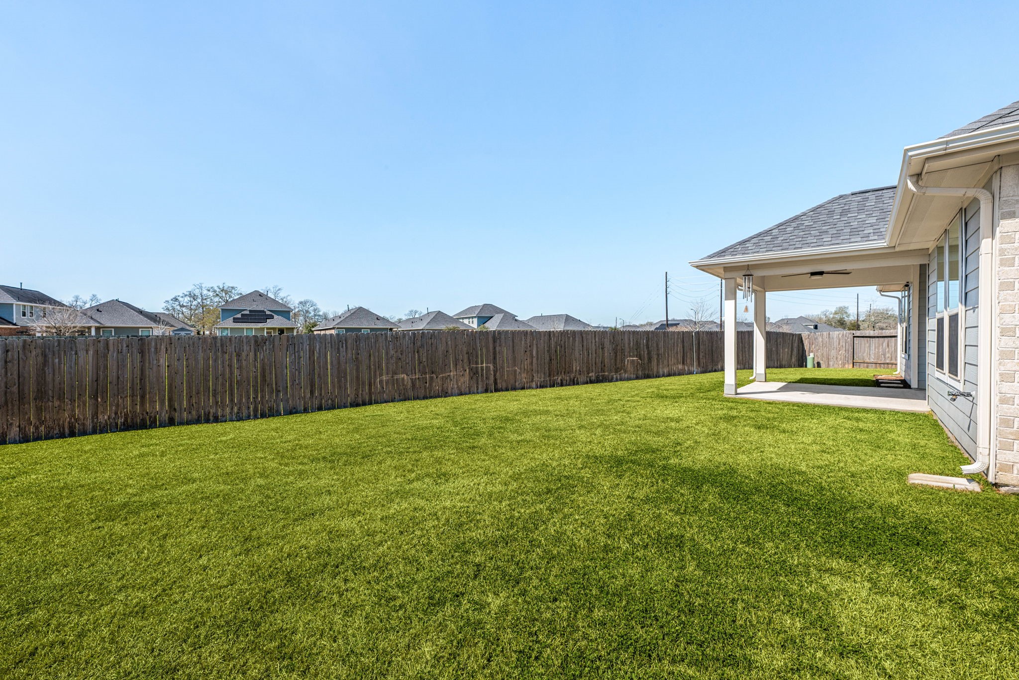 8414 Divot Trace Fulshear, TX 77441 - Photo 22 of 25 This spacious covered patio provides a seamless transition to the outdoors, offering a shaded retreat perfect for all-weather relaxation. The solid roofline integrates perfectly with the home's architecture, while the open-air design overlooks an expansive, level backyard. Fully enclosed by a private wood fence, this generous green space is a versatile blank canvas for your dream outdoor oasis.