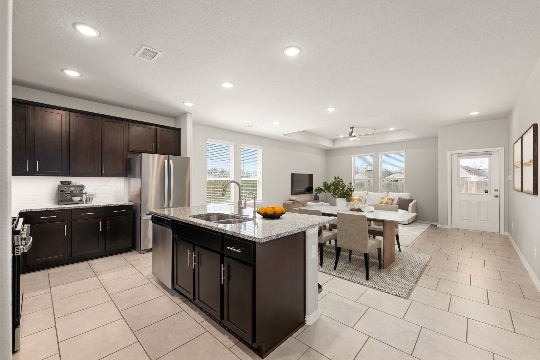 8414 Divot Trace Fulshear, TX 77441 - Photo 5 of 25 Experience an open-concept chef’s kitchen designed for both functionality and style. This modern space features sleek, dark cabinetry, upgraded granite countertops, and a generous island that serves as a central hub.