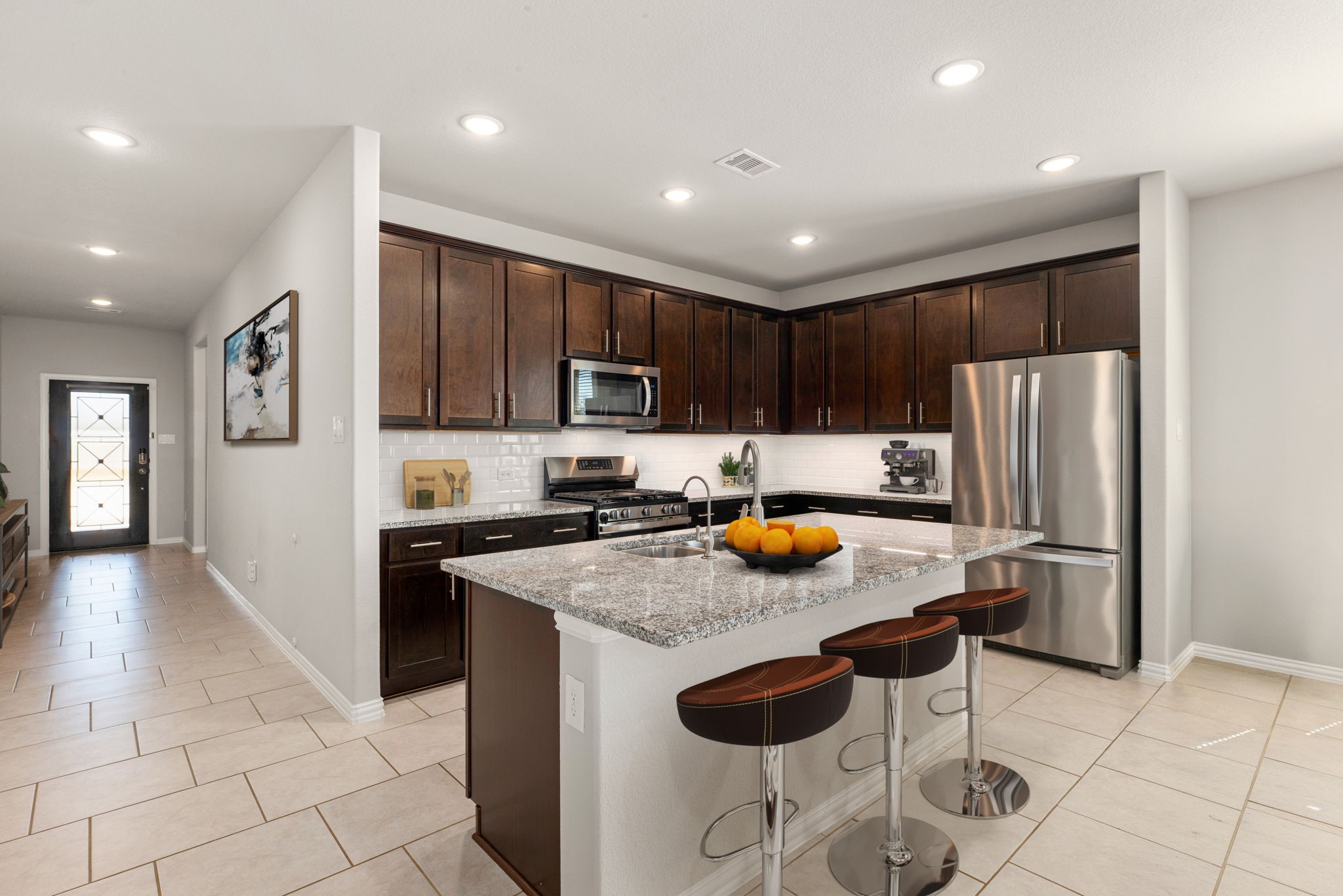 8414 Divot Trace Fulshear, TX 77441 - Photo 6 of 25 A large center island provides ample prep space and a breakfast bar, while recessed lighting and neutral tile flooring create a bright, airy feel throughout the heart of the home.