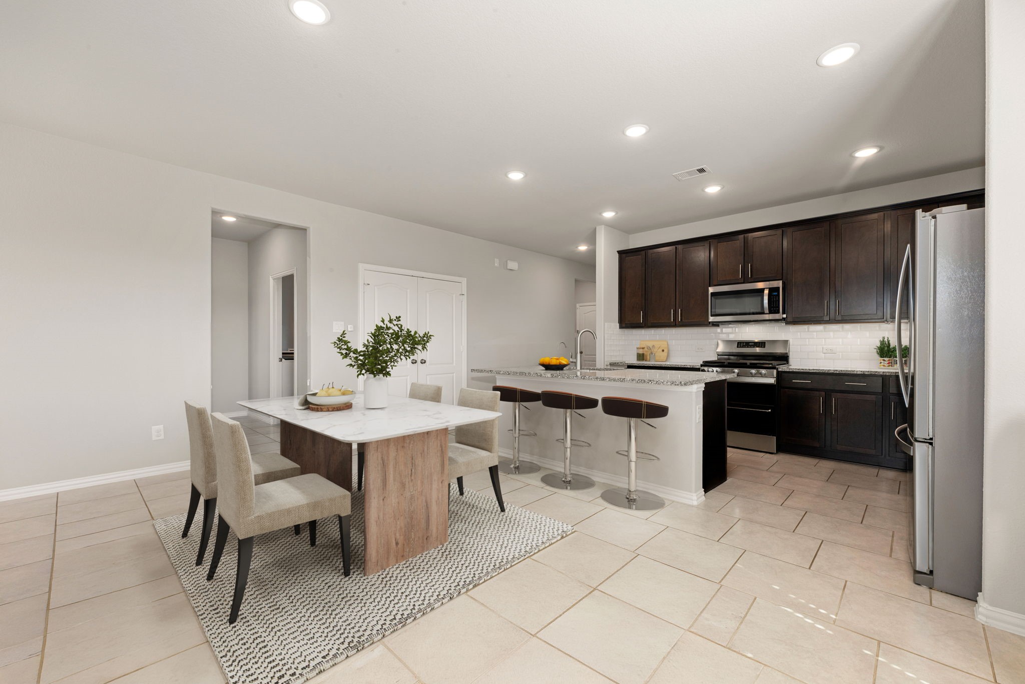8414 Divot Trace Fulshear, TX 77441 - Photo 9 of 25 The room is illuminated by recessed lighting and flows seamlessly into the bright dining and living areas, highlighted by large windows and neutral-toned flooring.