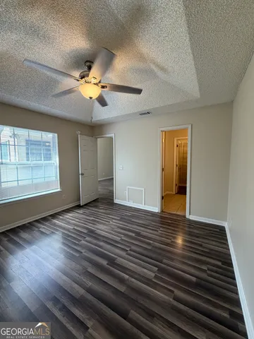 a view of empty room with wooden floor and fan