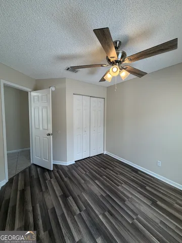 a view of an empty room with wooden floor and chandelier fan