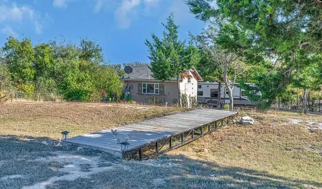 a view of a house with a yard and a large tree