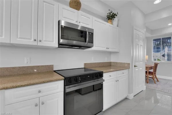 a kitchen with granite countertop white cabinets stainless steel appliances and a counter space