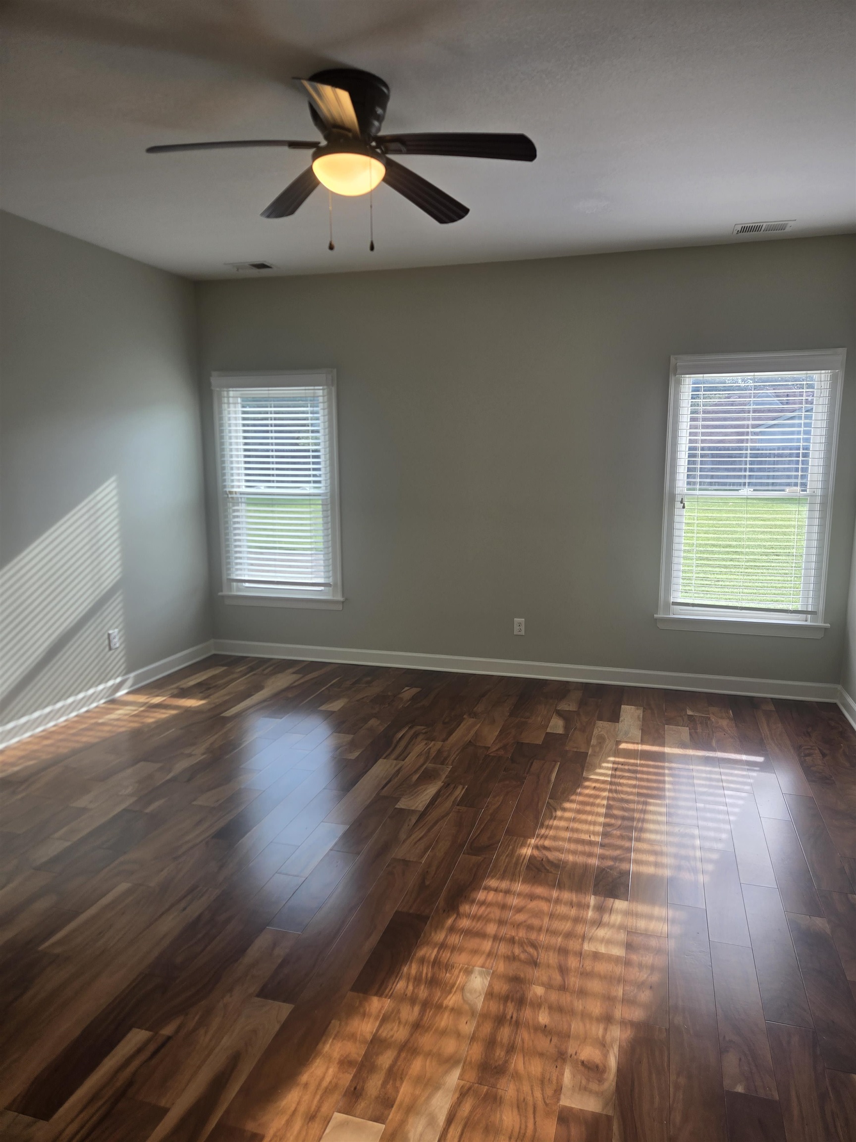 737 Steeple Ridge Cove Collierville, TN 38017 - Photo 12 of 21 Wood-finish flooring, two window openings with blinds, light green wall paint, and a ceiling fan with integrated lighting